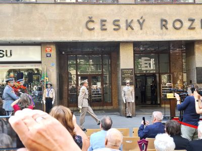 Před budovou Český rozhlas probíhá veřejná akce s vystupujícími a publikem na náměstí.