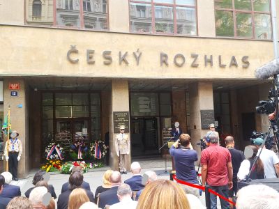 Dav lidí sleduje vystoupení před budovou s nápisem Český rozhlas, u vchodu a pódiu.