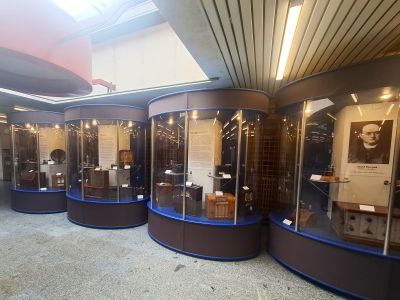 Kruhové vitríny s exponáty v muzeu, skleněné skříně a osvětlené panely v chodbě.